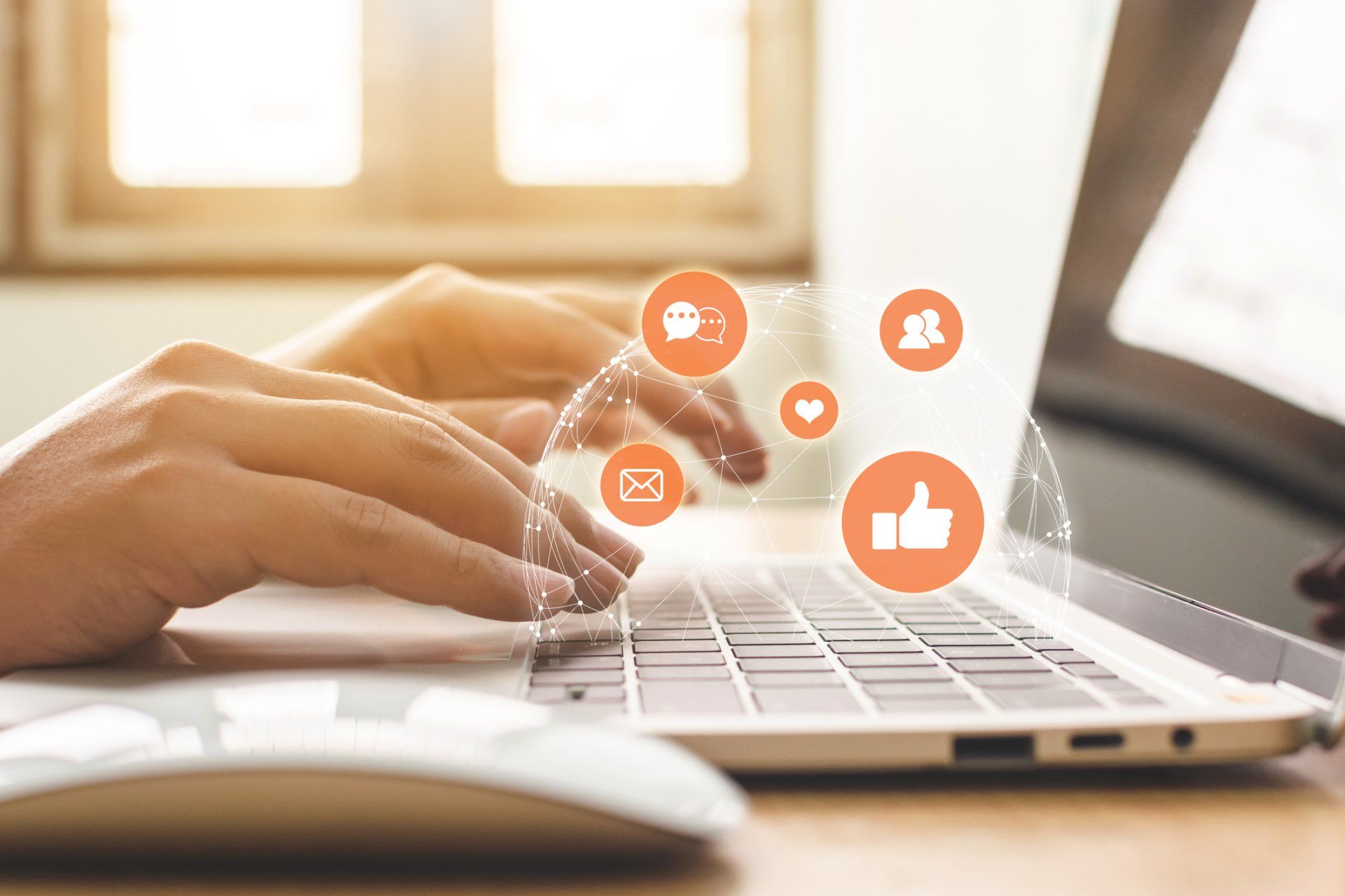 A person is typing on a laptop with social media icons coming out of it