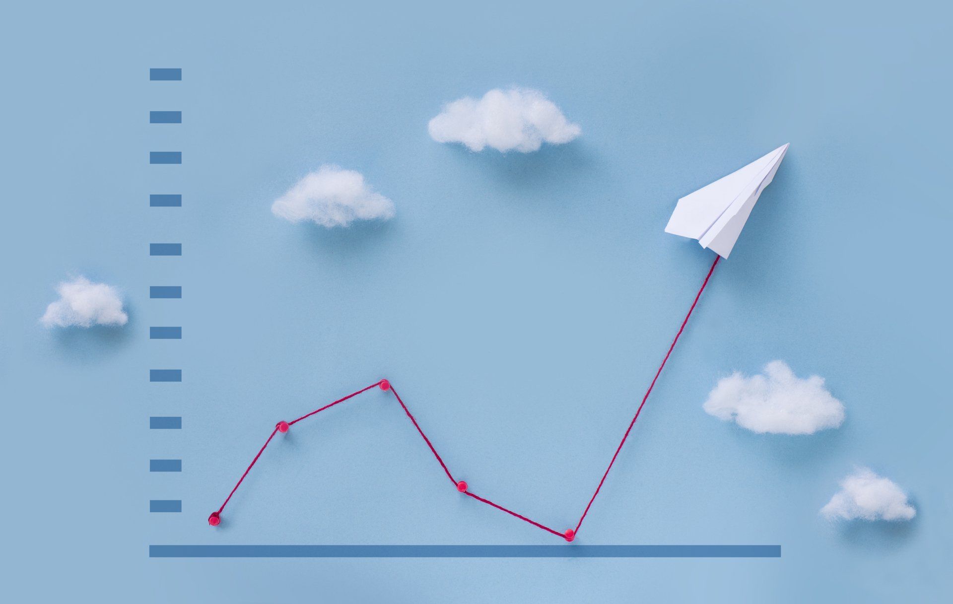 A paper airplane is flying in the sky above a graph.
