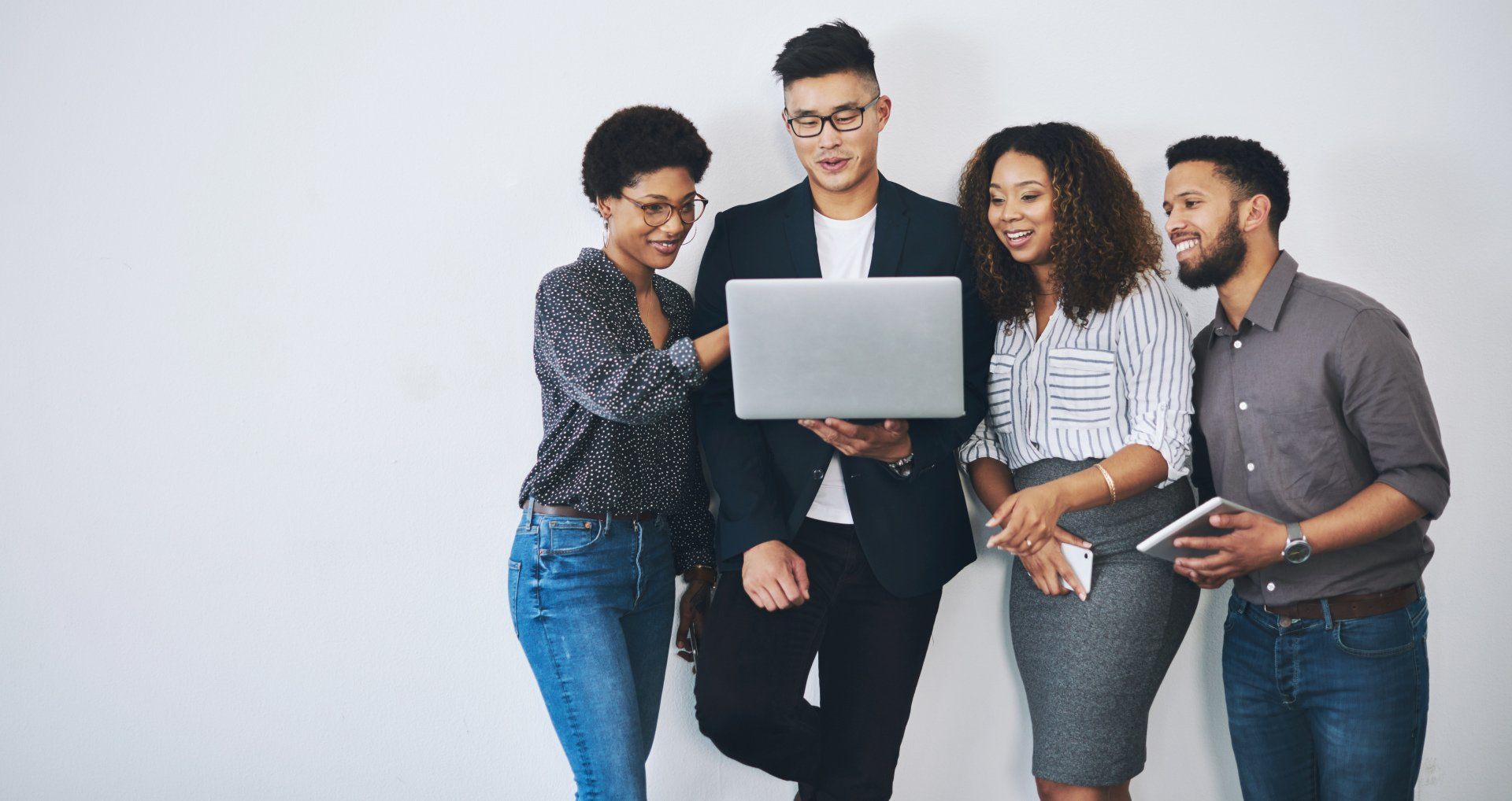 A group of people are standing around a laptop computer.
