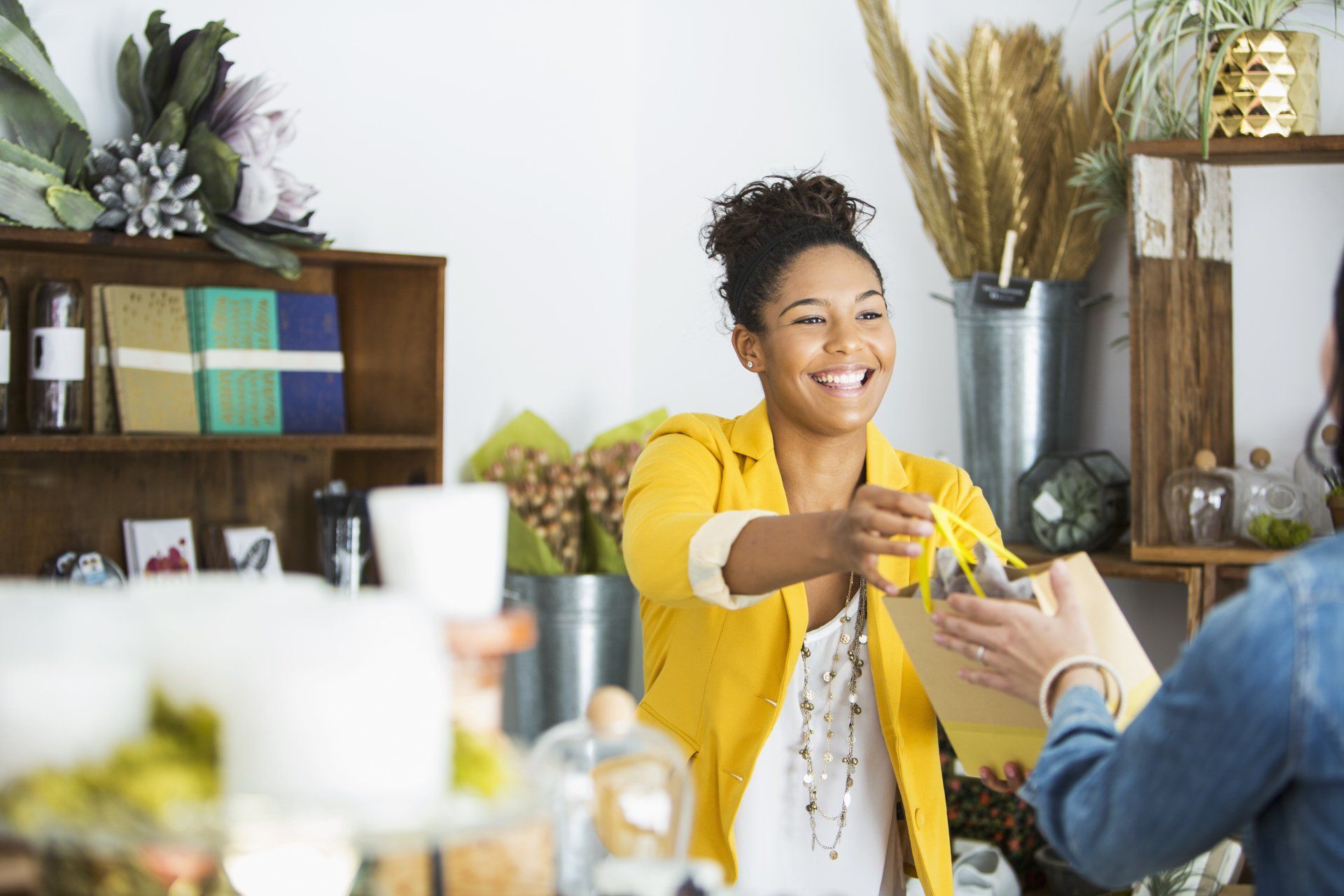A woman in a yellow jacket is giving a gift to another woman