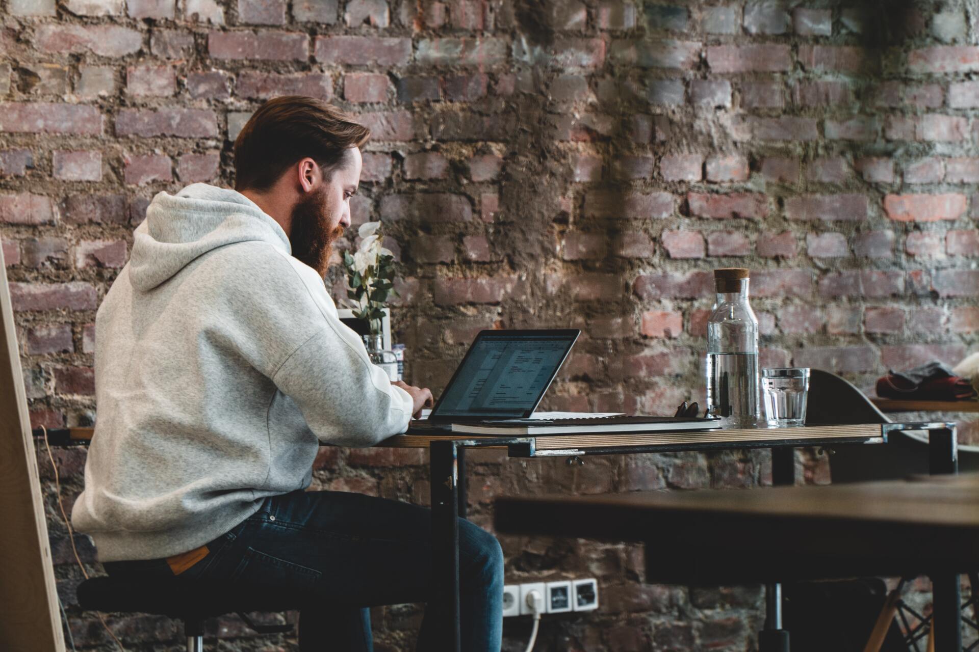 A man is sitting at a table using a laptop computer.