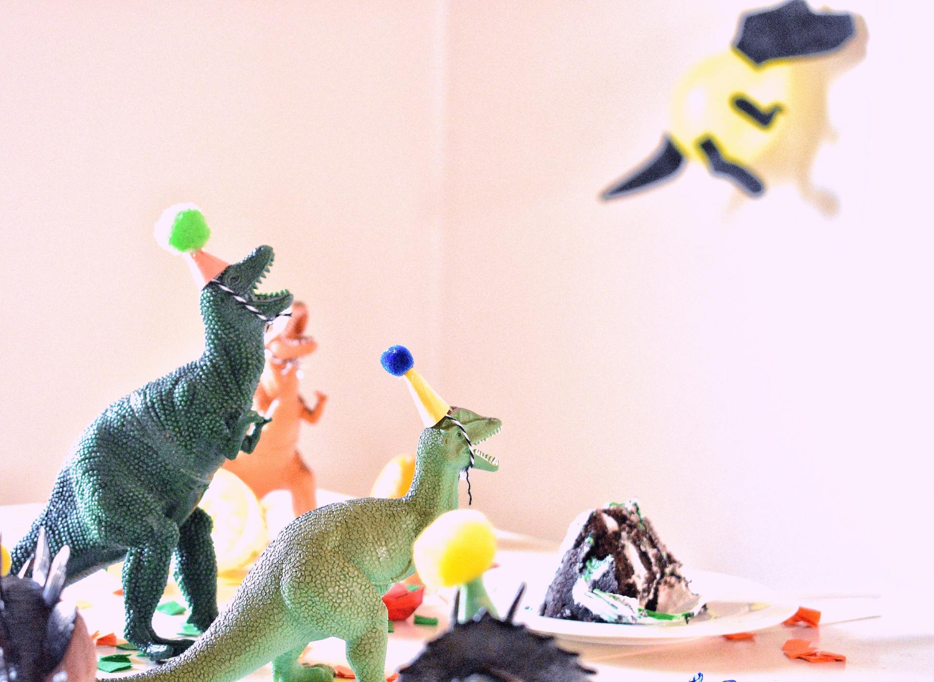 A group of toy dinosaurs wearing party hats