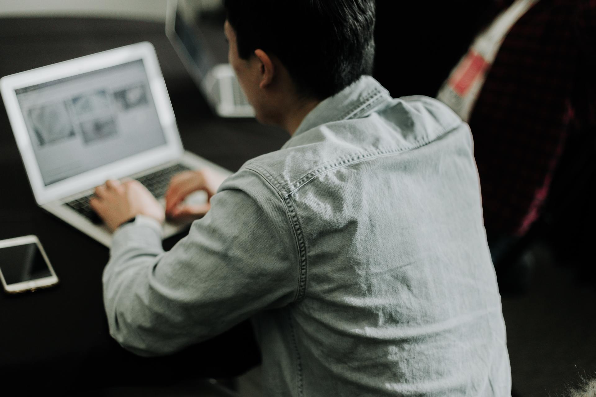 A man is sitting at a desk using a laptop computer.