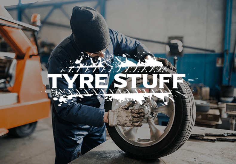 A man is working on a tire with the words tyre stuff behind him