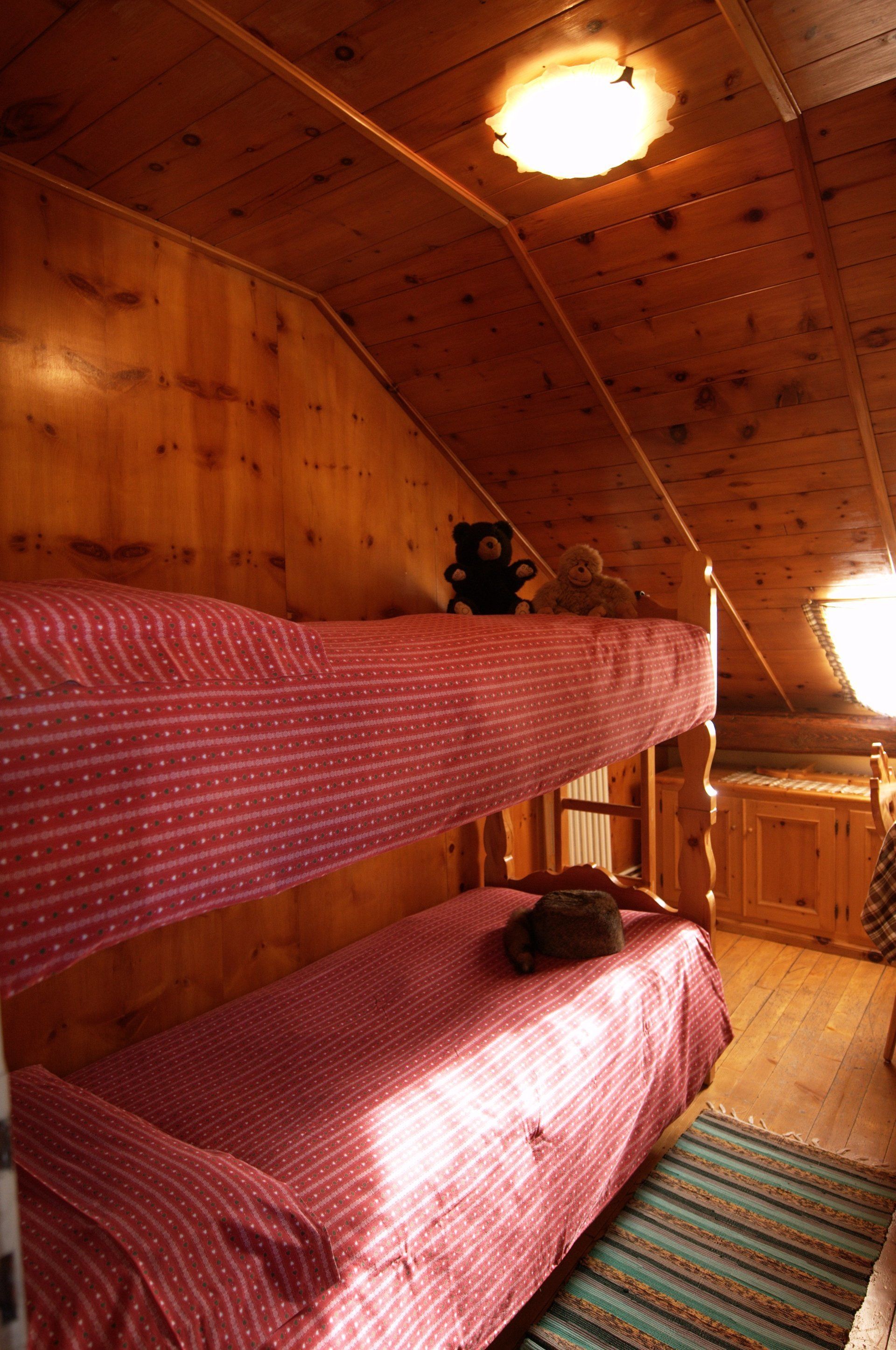 Un letto a castello con un orsacchiotto sopra in una stanza di legno.