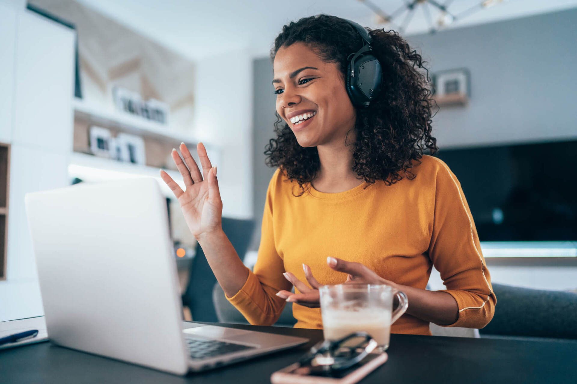 A woman wearing headphones is having a video call on her laptop computer.