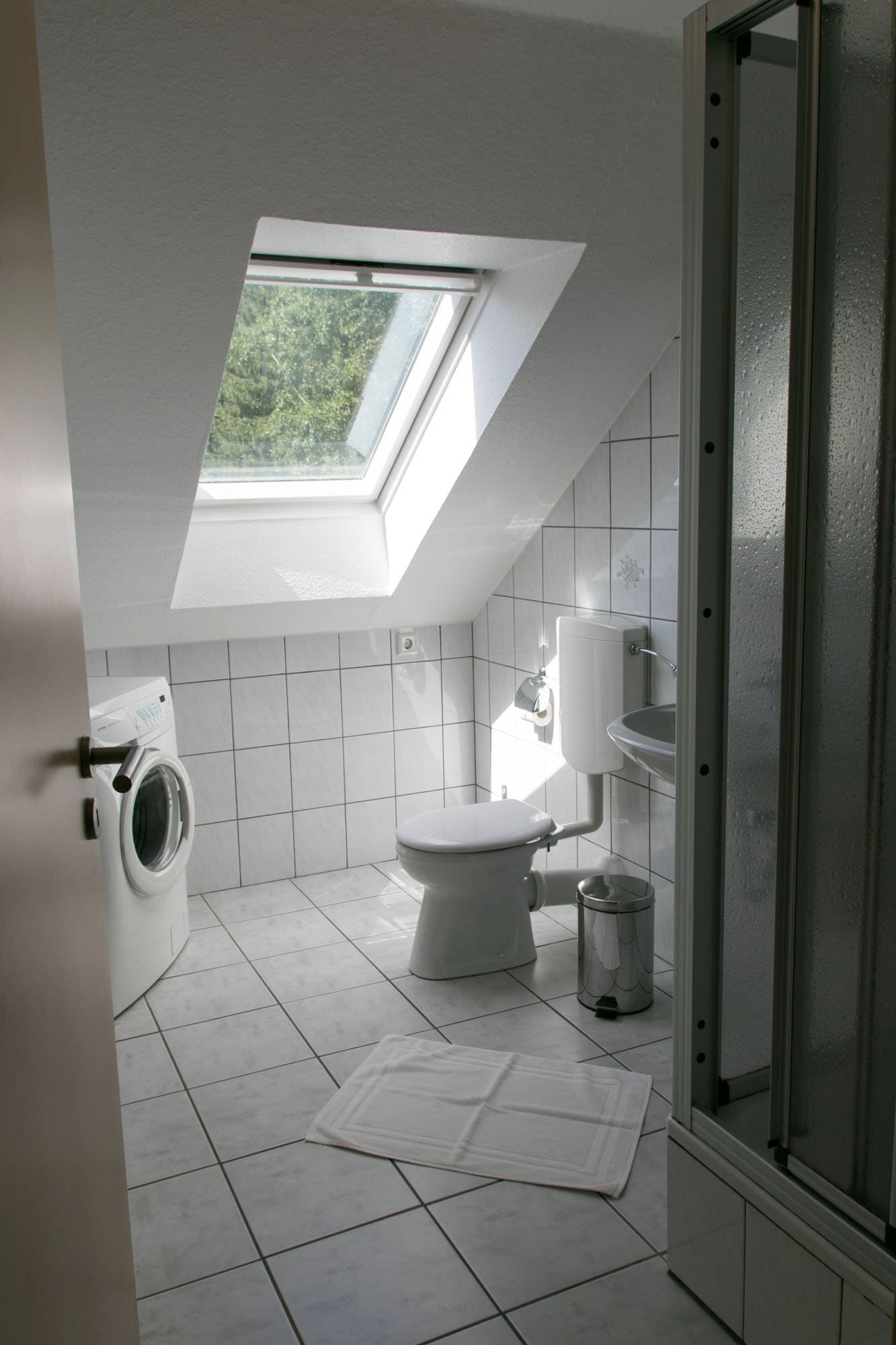 Ein Badezimmer mit Toilette, Waschmaschine und Trockner und einem Oberlicht.