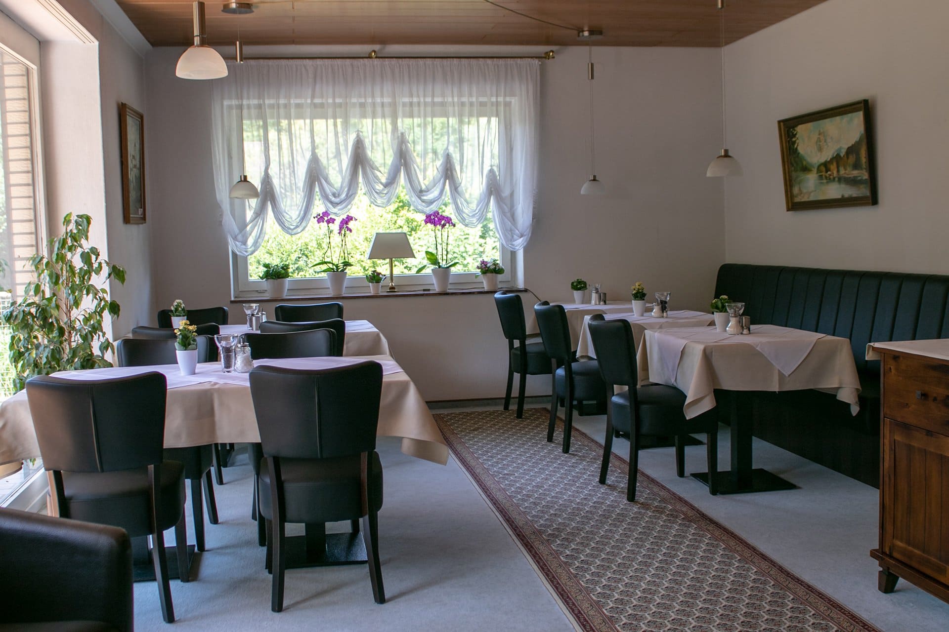 Ein Esszimmer mit Tischen und Stühlen und einem Fenster