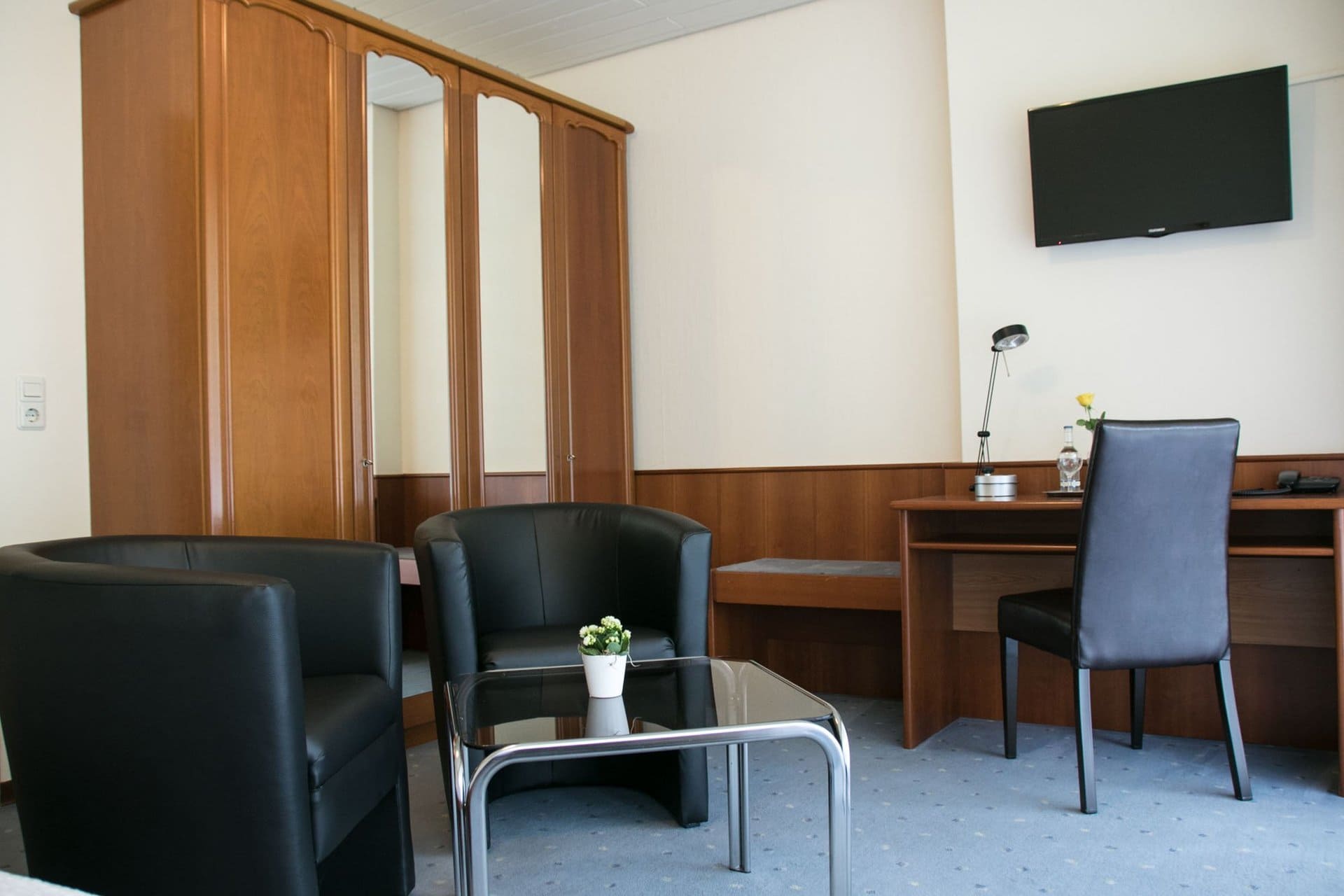 Ein Hotelzimmer mit zwei Stühlen, einem Schreibtisch und einem Flachbildfernseher