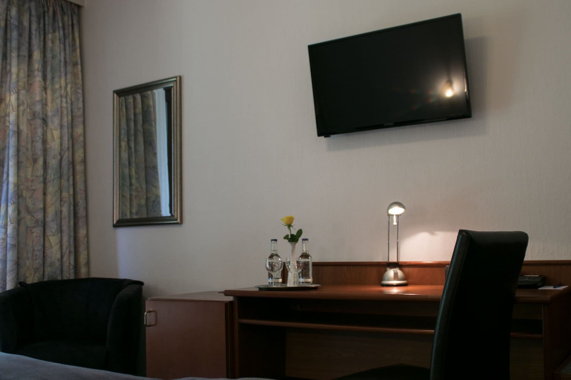 Ein Hotelzimmer mit einem Schreibtisch und Stühlen und einem Flachbildfernseher an der Wand.