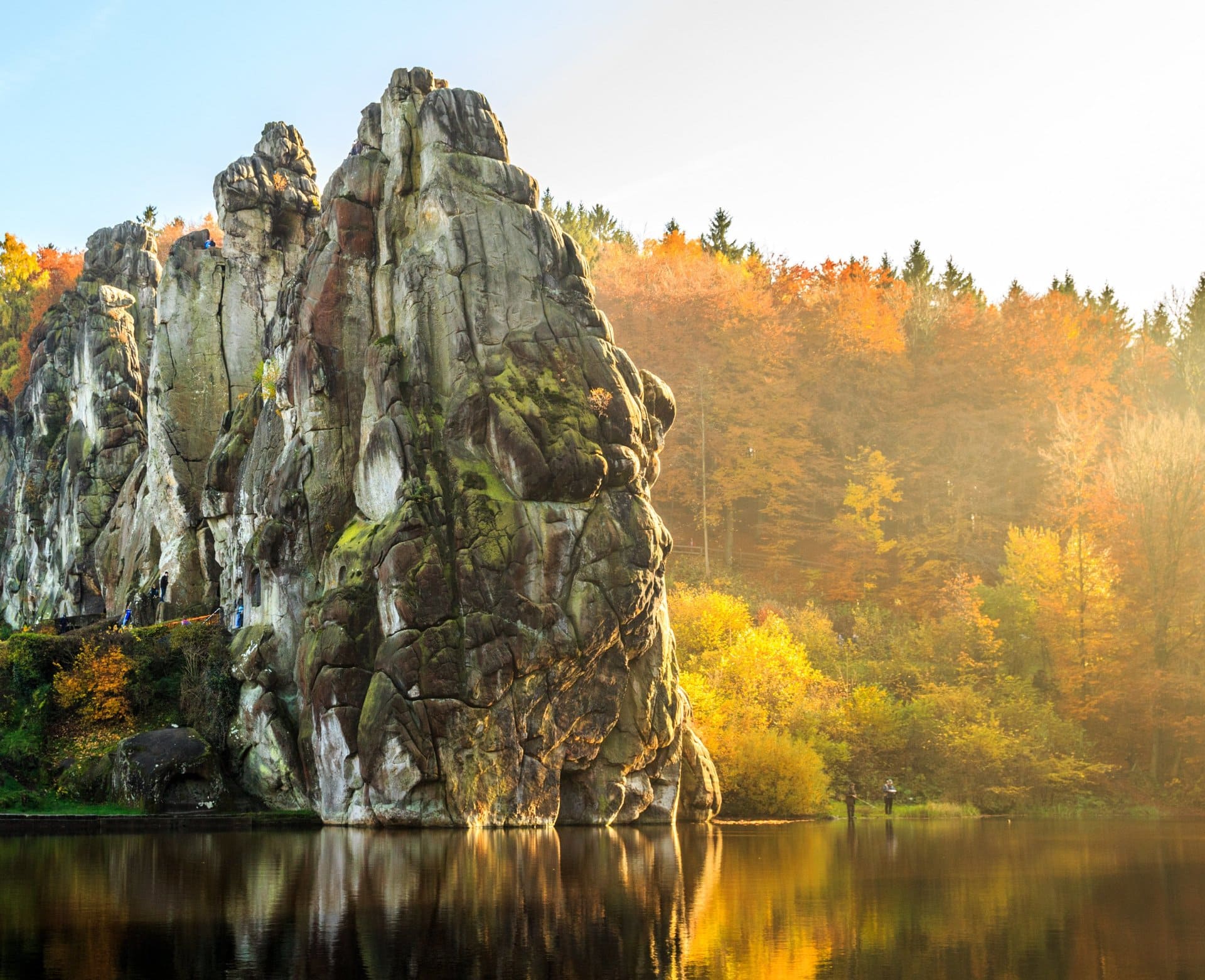 In der Mitte eines Sees, umgeben von Bäumen, befindet sich ein großer Felsen.