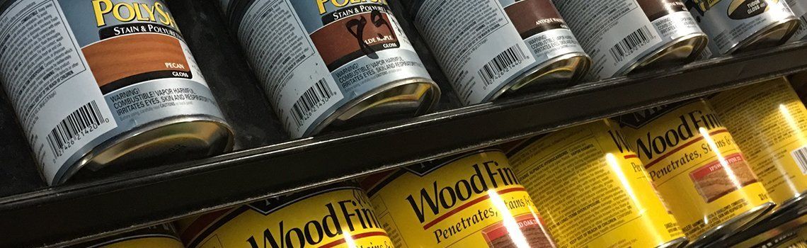 Wood stain cans on shelves, various shades of brown and yellow.