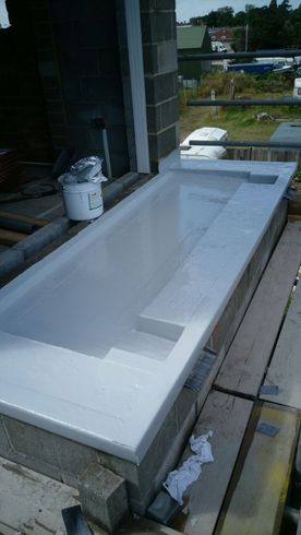 a bucket of white paint sits next to a bathtub