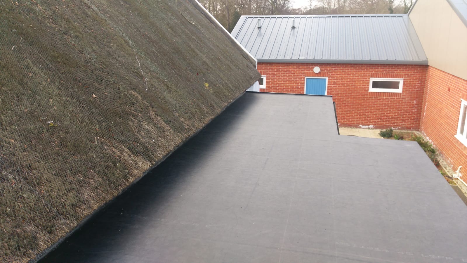 a brick building with a blue door and a black roof