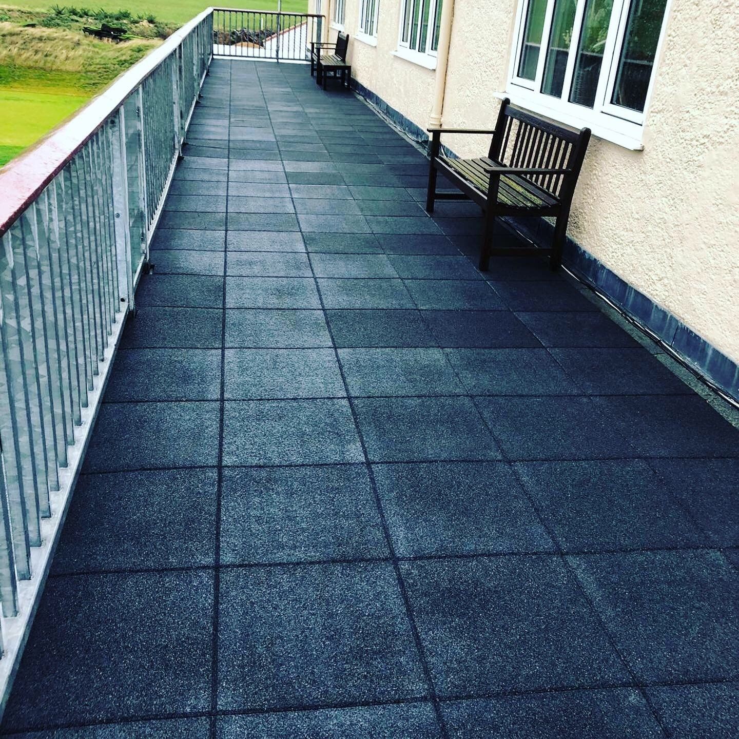 a balcony with black tiles and a wooden bench