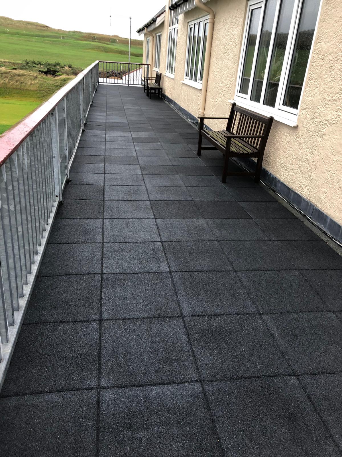 a balcony with black tiles and a wooden bench