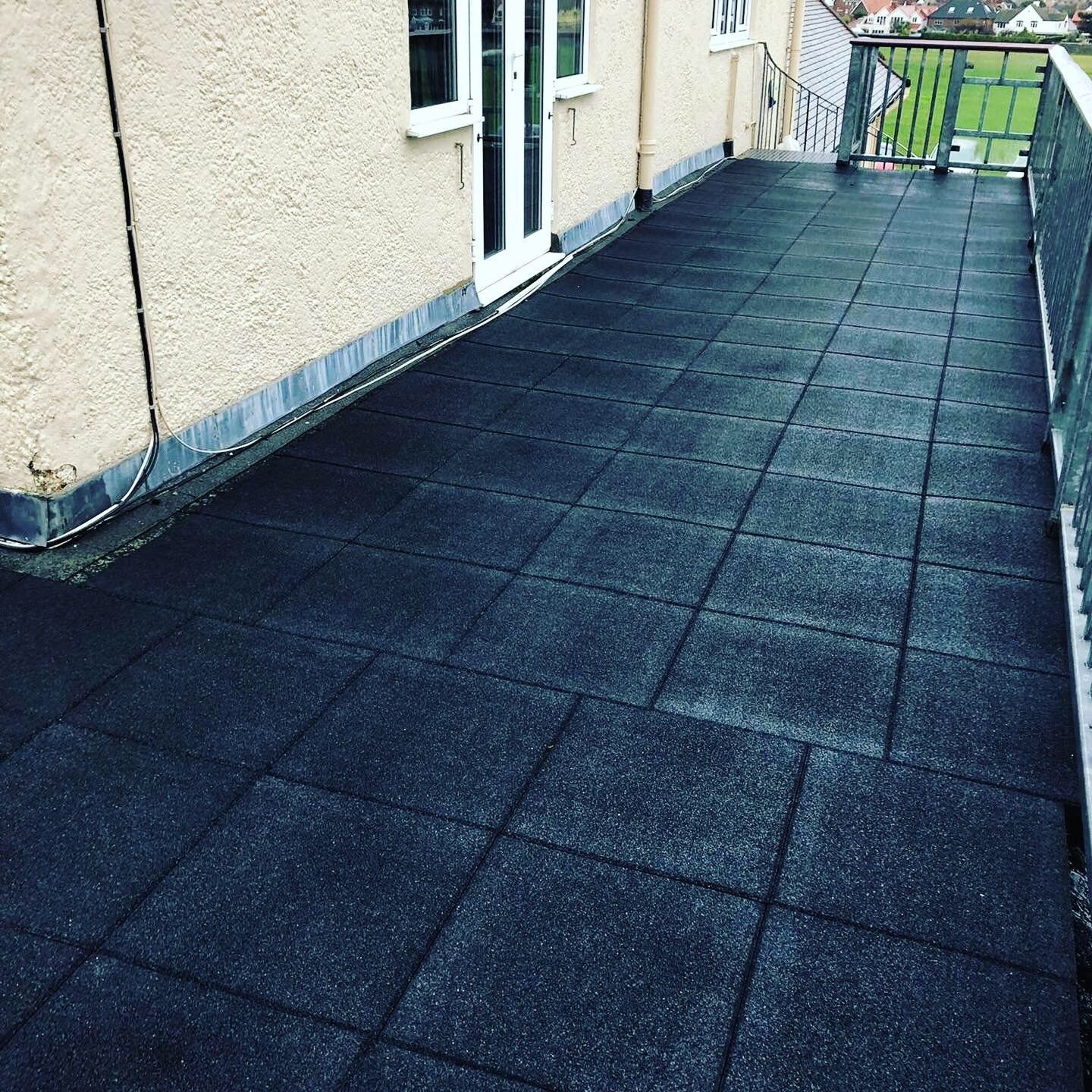 a balcony with black tiles and a railing
