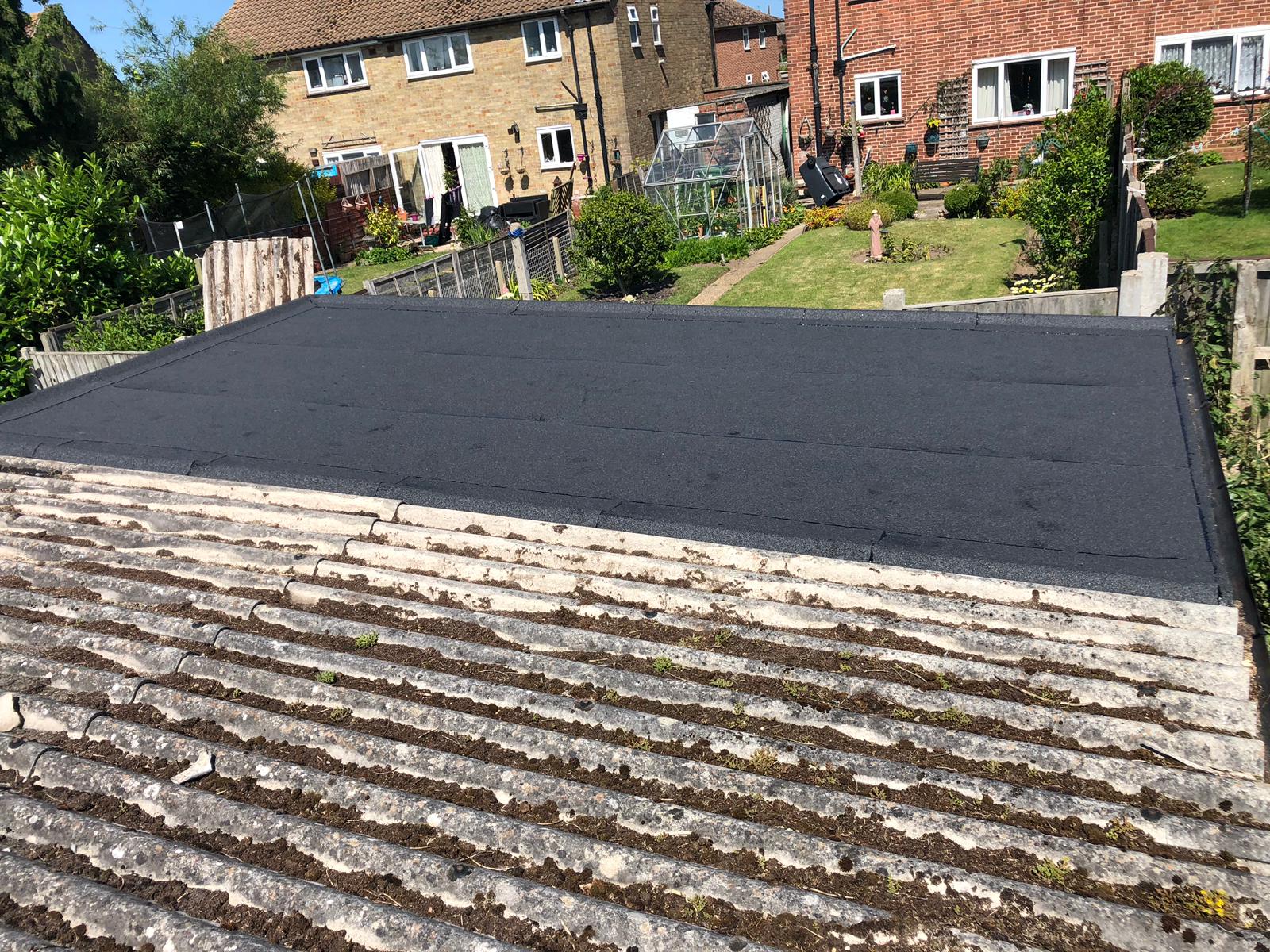 a roof with a black roof and a garden in the background