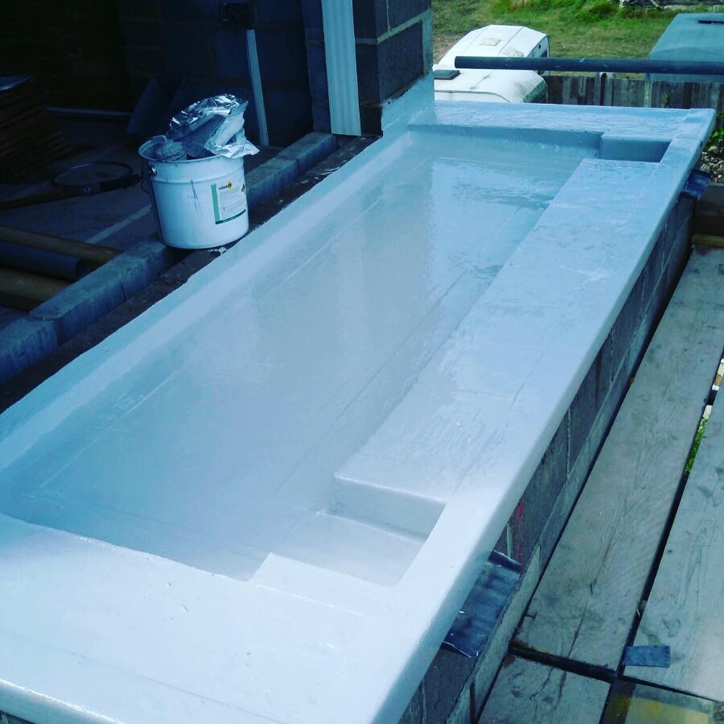 a bucket of white paint sits next to a bathtub