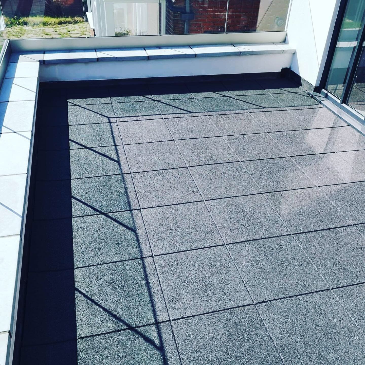 a balcony with black tiles and a white bench