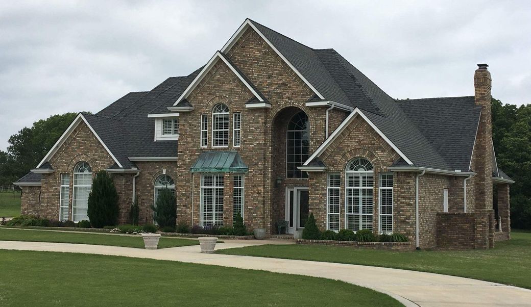 white house with black tiled roof installed by roofing contractors of Jenks, OK