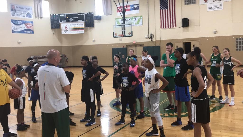 A group of people are standing around a basketball court.
