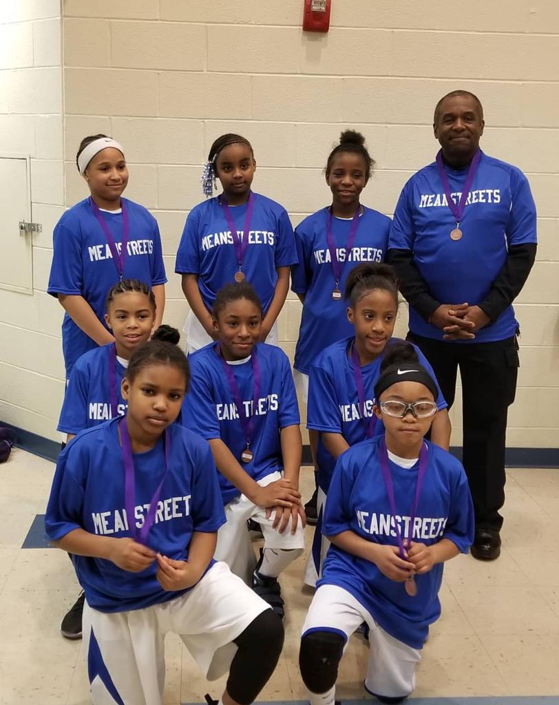 A group of young girls are posing for a picture with medals around their necks.
