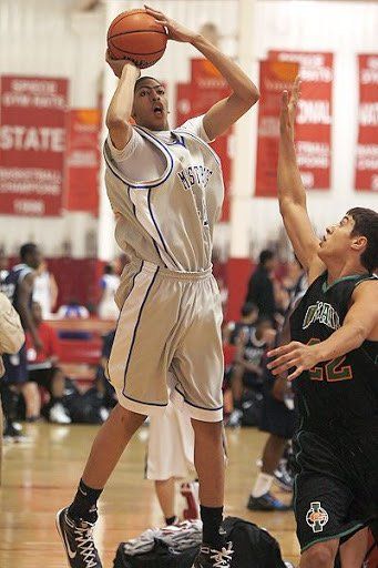 Two basketball players are playing a game of basketball on a court.