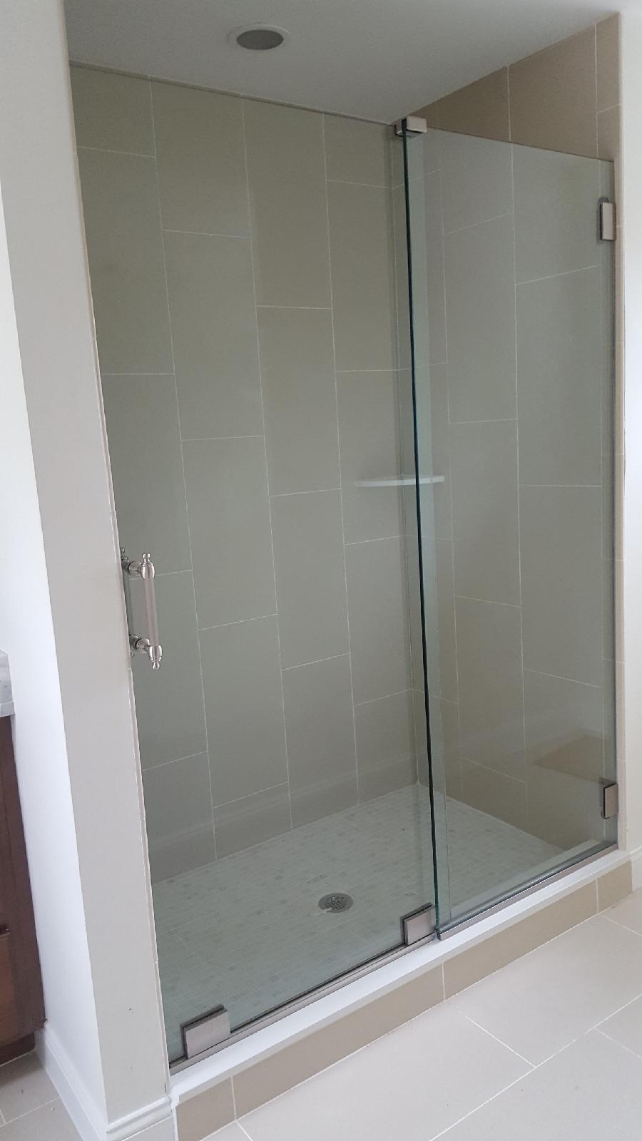 Glass shower enclosure with a door and a fixed panel; tile walls and floor.