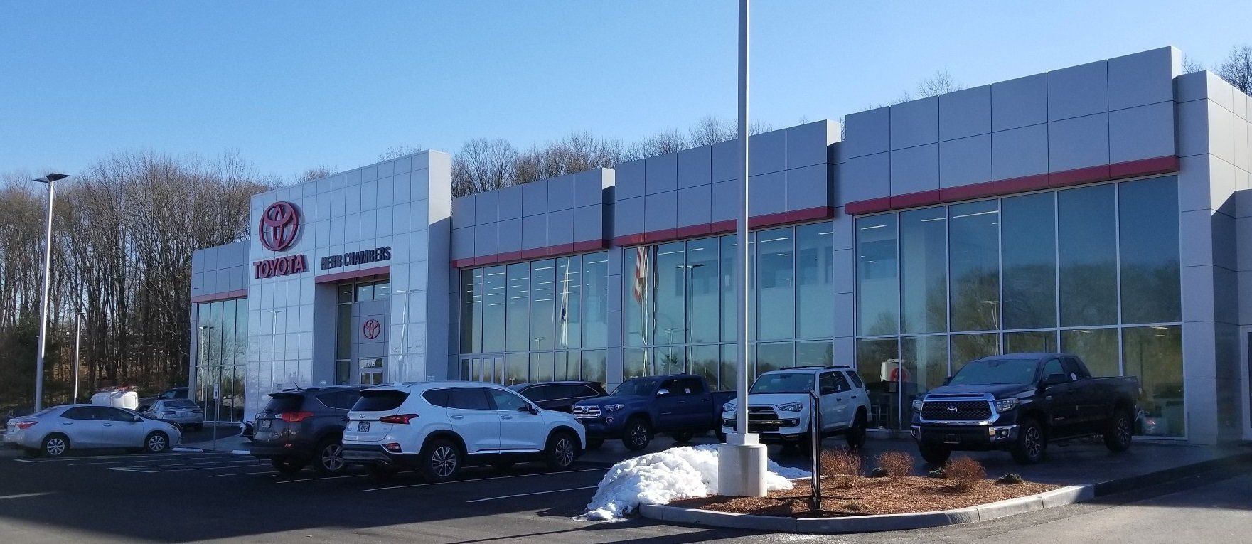 A Toyota dealership building with cars parked in front on a sunny day.