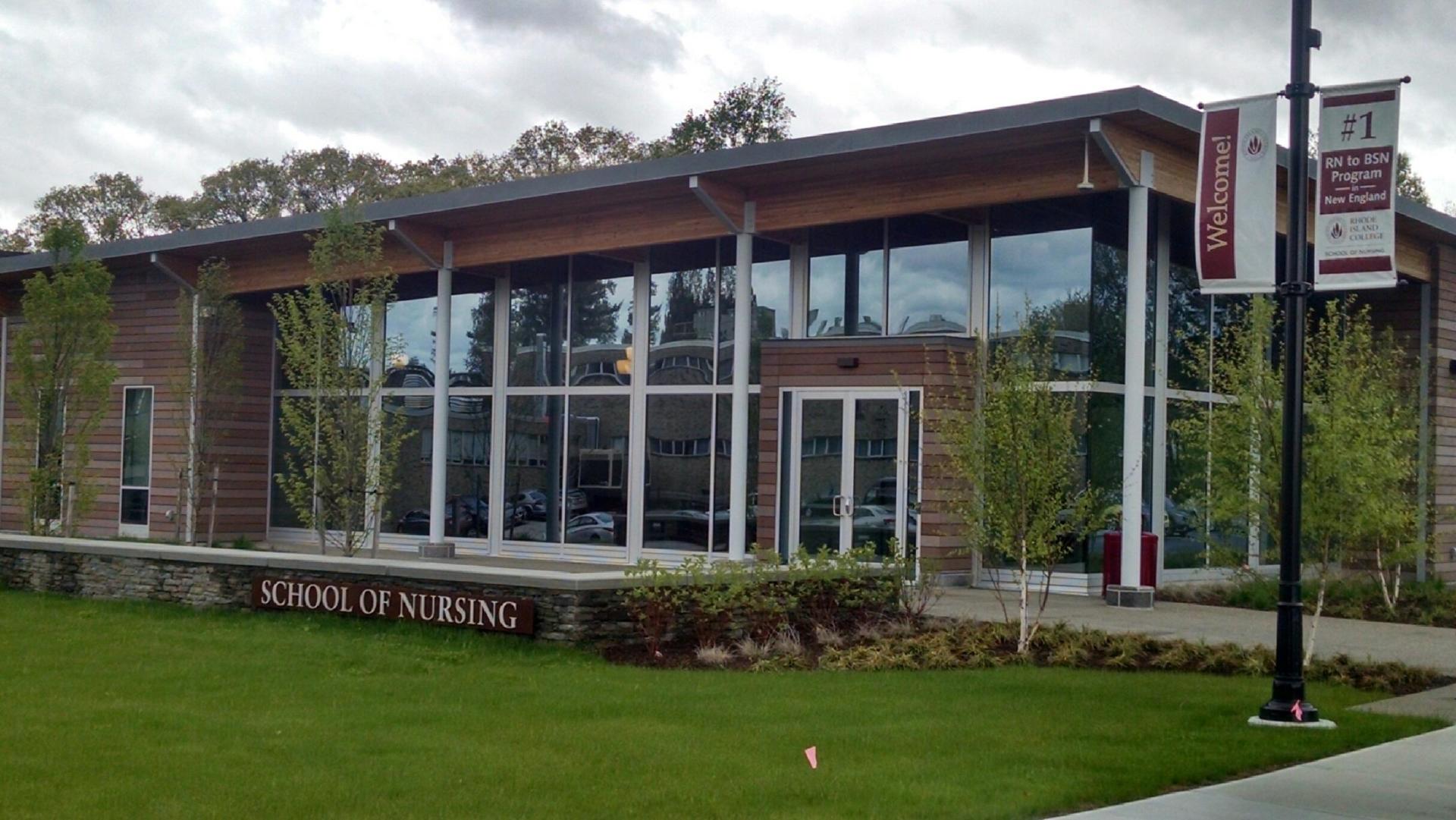 School of Nursing building with glass windows, a grassy lawn, and a banner.