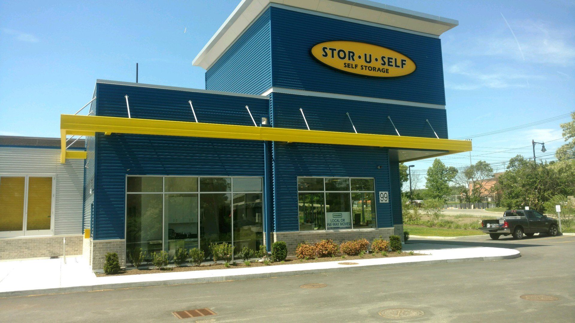 Stor-U-Self self-storage building with blue exterior, yellow trim, and a truck in the driveway.