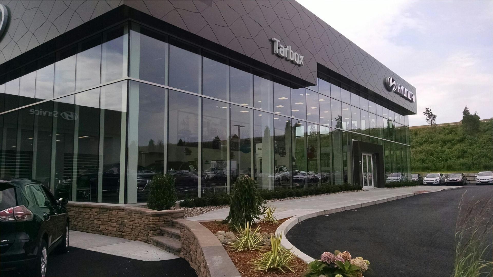 Exterior view of a modern car dealership building with large glass windows; 