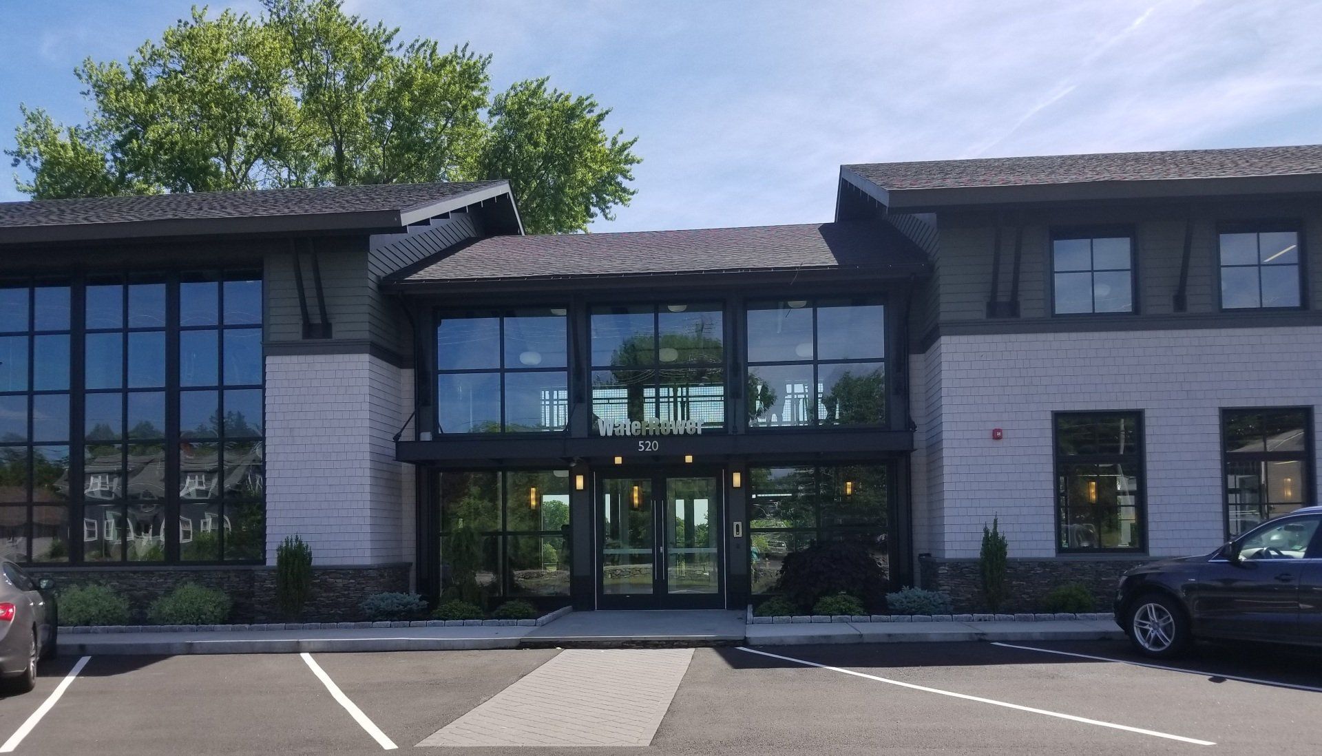 Building entrance with glass doors, windows, and stone facade; blue sky.