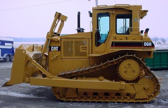 Yellow Caterpillar D6H bulldozer, tracks, blade, black exhaust stack, parked outdoors.