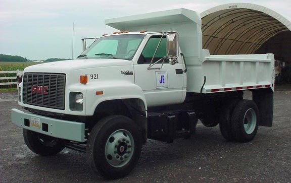 White GMC dump truck, side view, parked outdoors.