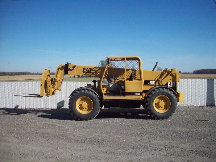 Yellow Caterpillar telehandler with forks parked outdoors.
