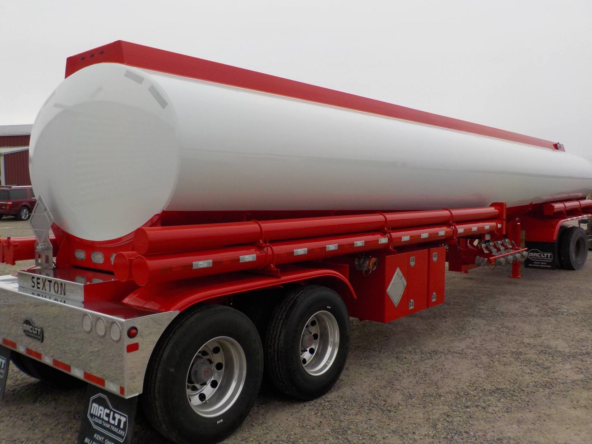 White and red tanker trailer with silver accents, parked outdoors.