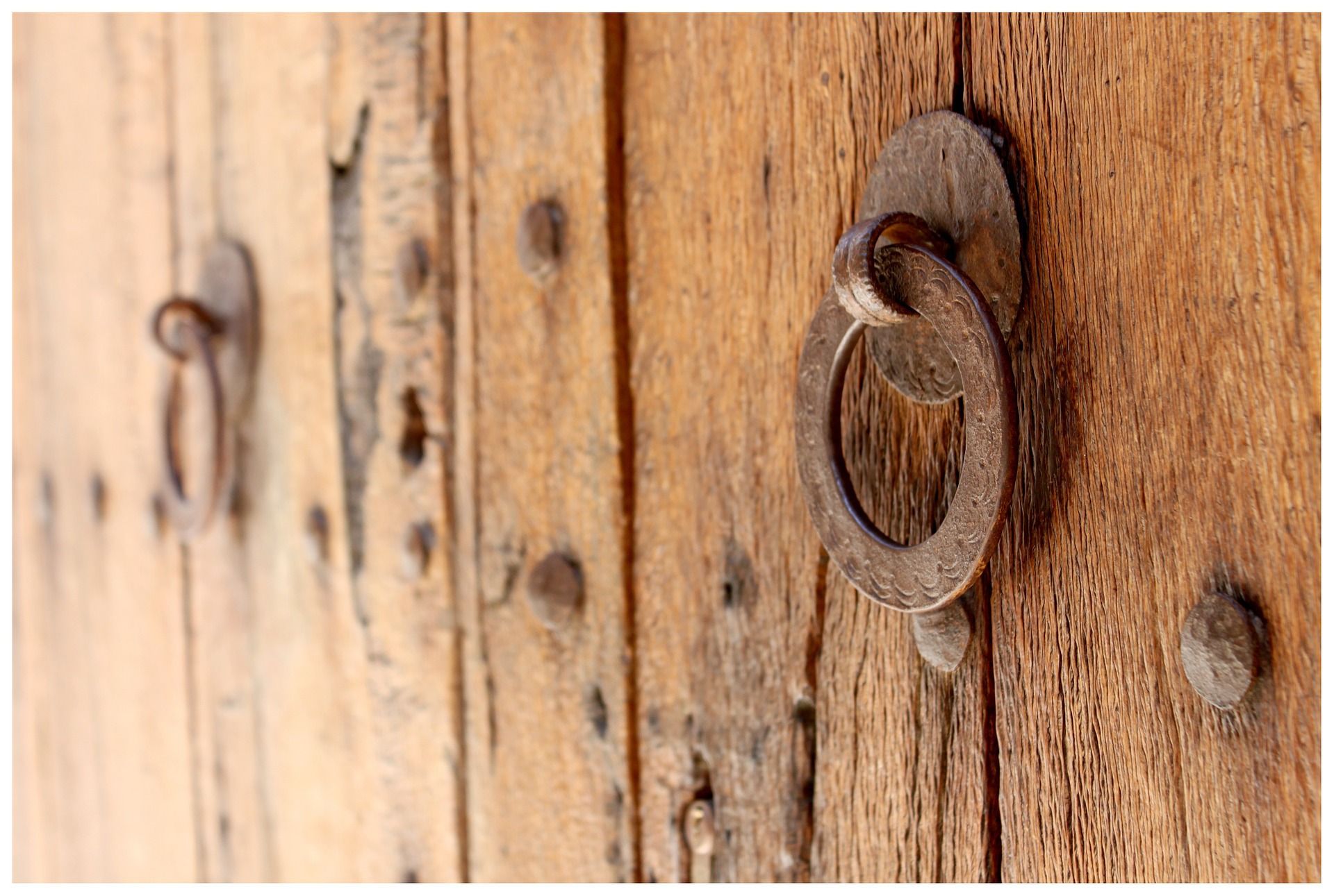 A close up of a wooden door with a metal ring on it.