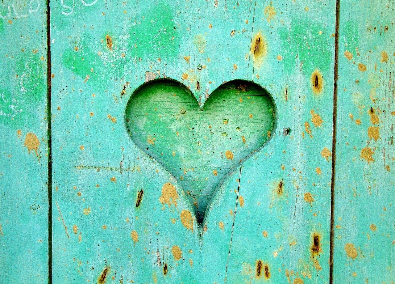 A heart is carved into a blue wooden door.