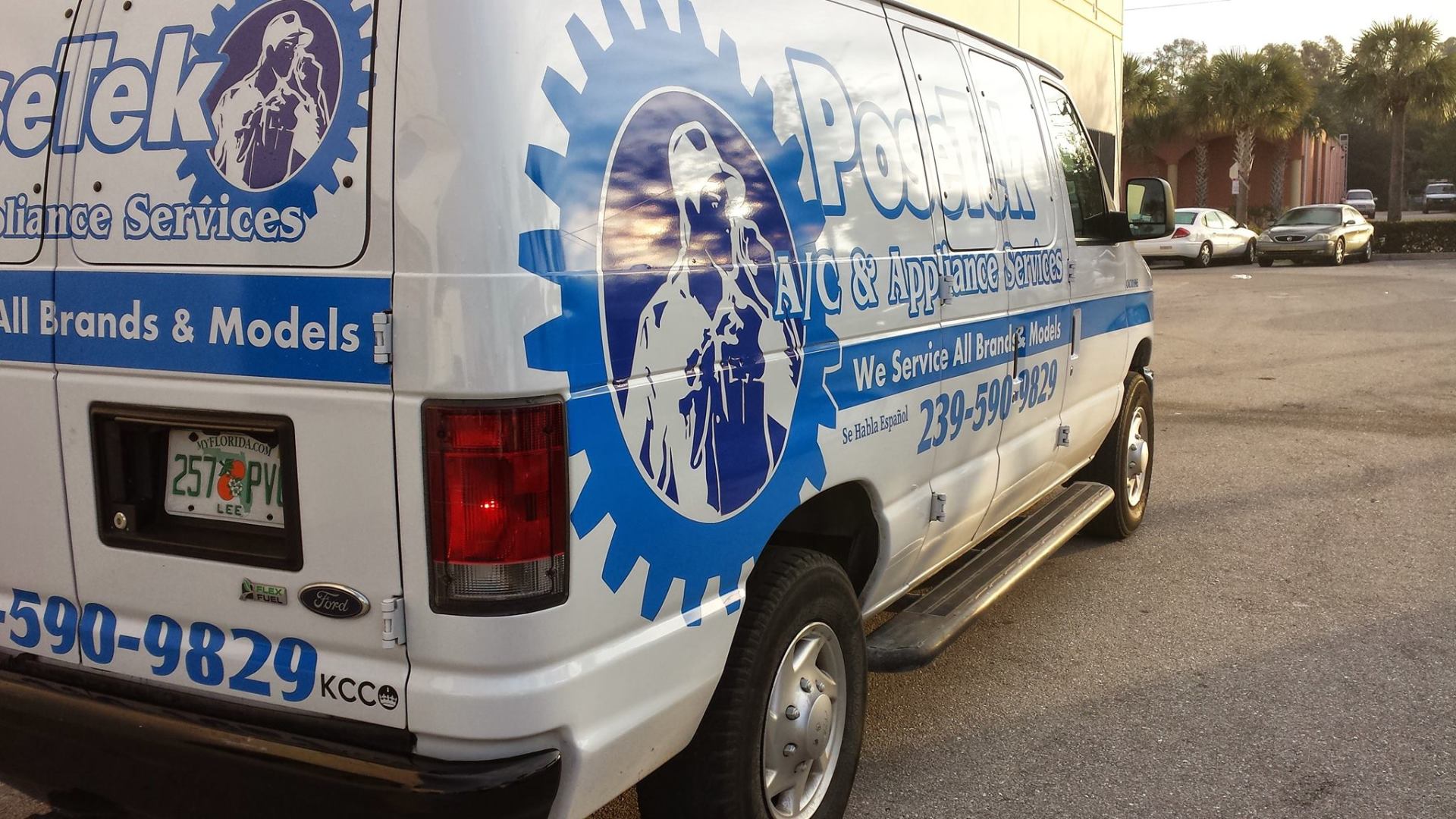 White service van with blue logo, parked outdoors.