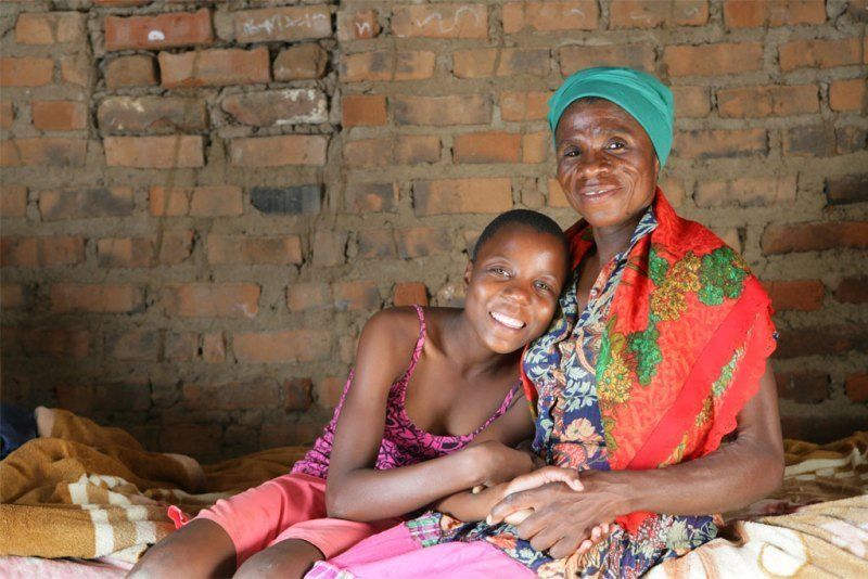 Two women sitting in front of a brick wall.