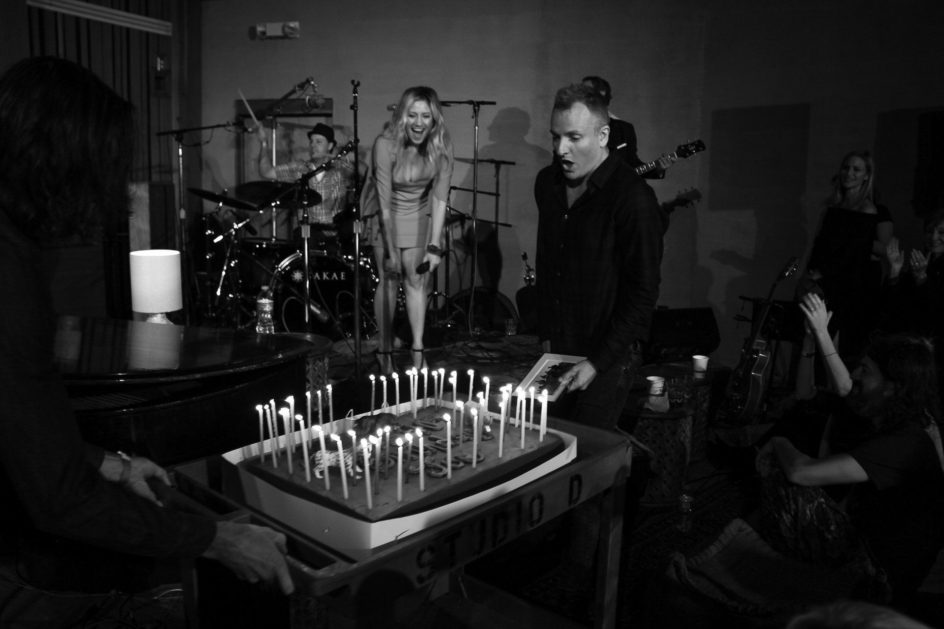 A group of people are standing around a cake with candles on it.