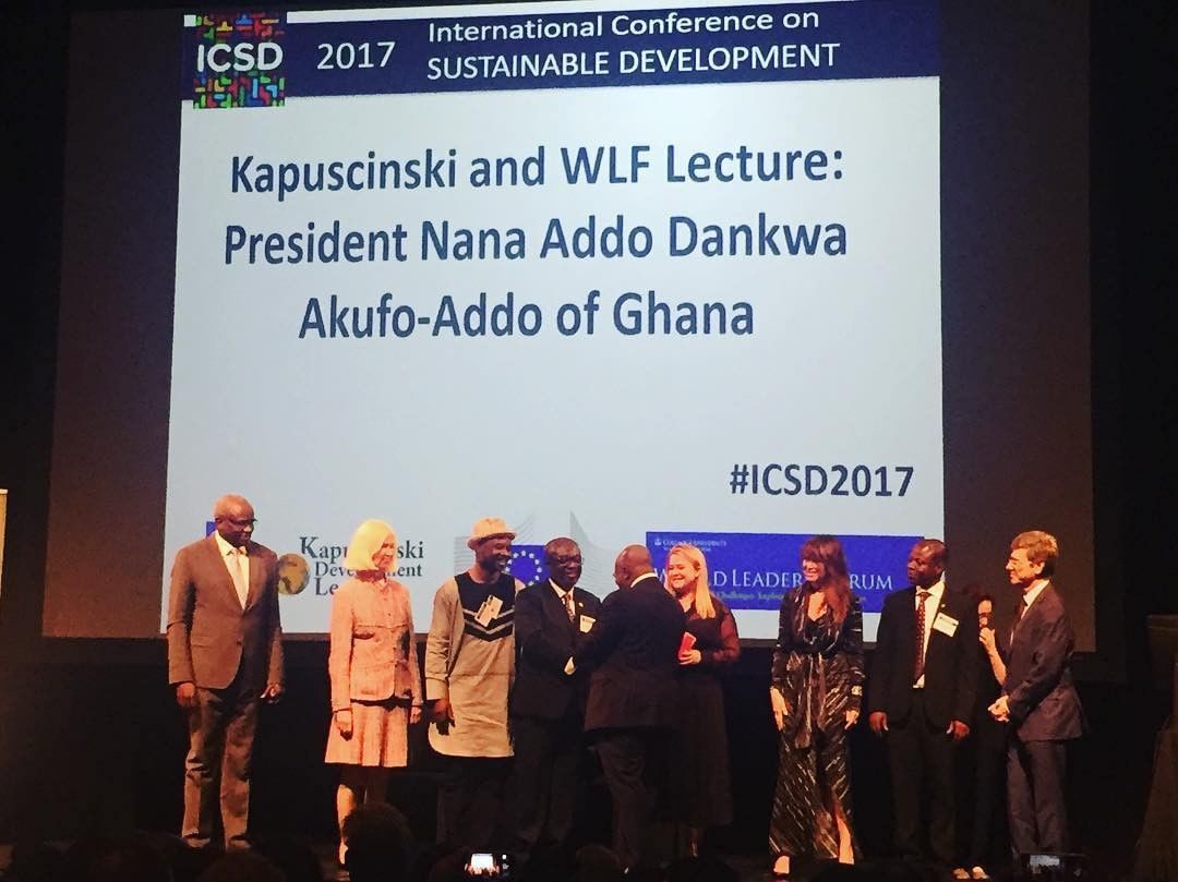 People on a stage with a screen mentioning President Akufo-Addo of Ghana at an international conference.