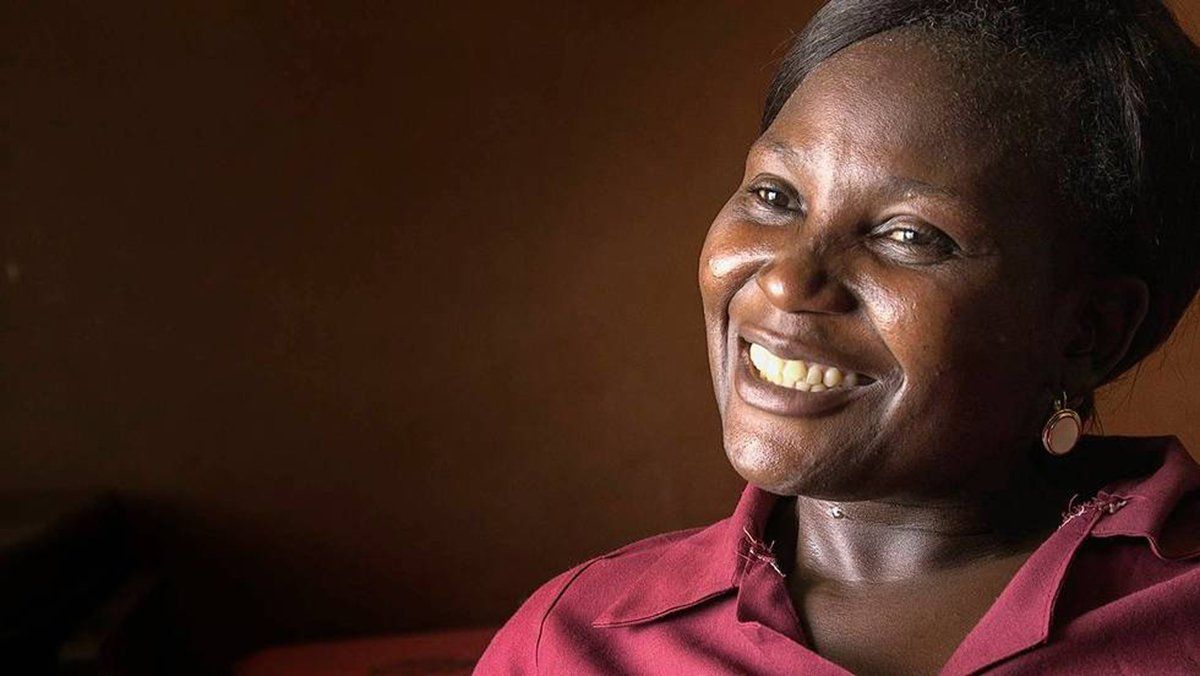 A women in with a red collared shirt with gold earrings smiling