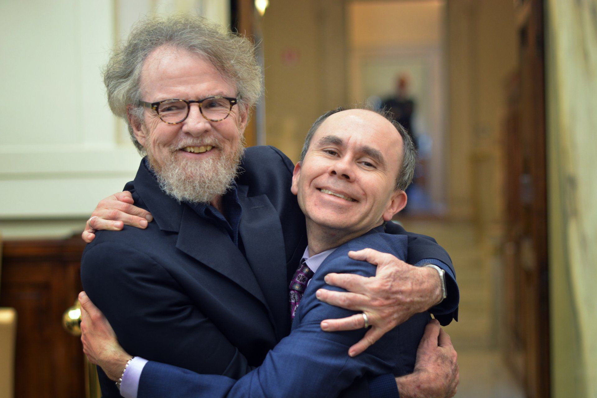 Two men embracing at the Ethics in Action Online Course Meeting