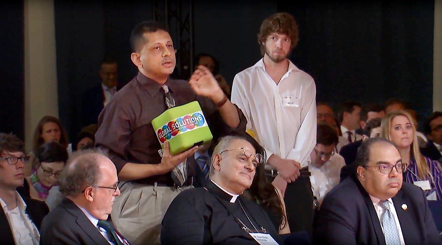 A group of people are sitting in a room and one man is holding a box that says ' a ' on it