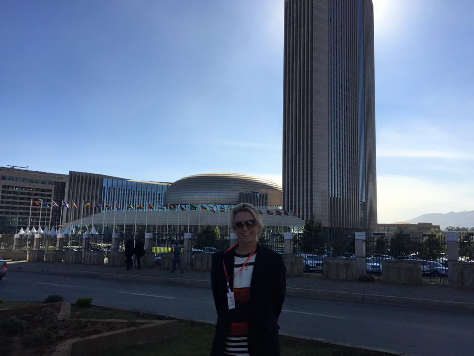 A woman is standing in front of a large building.