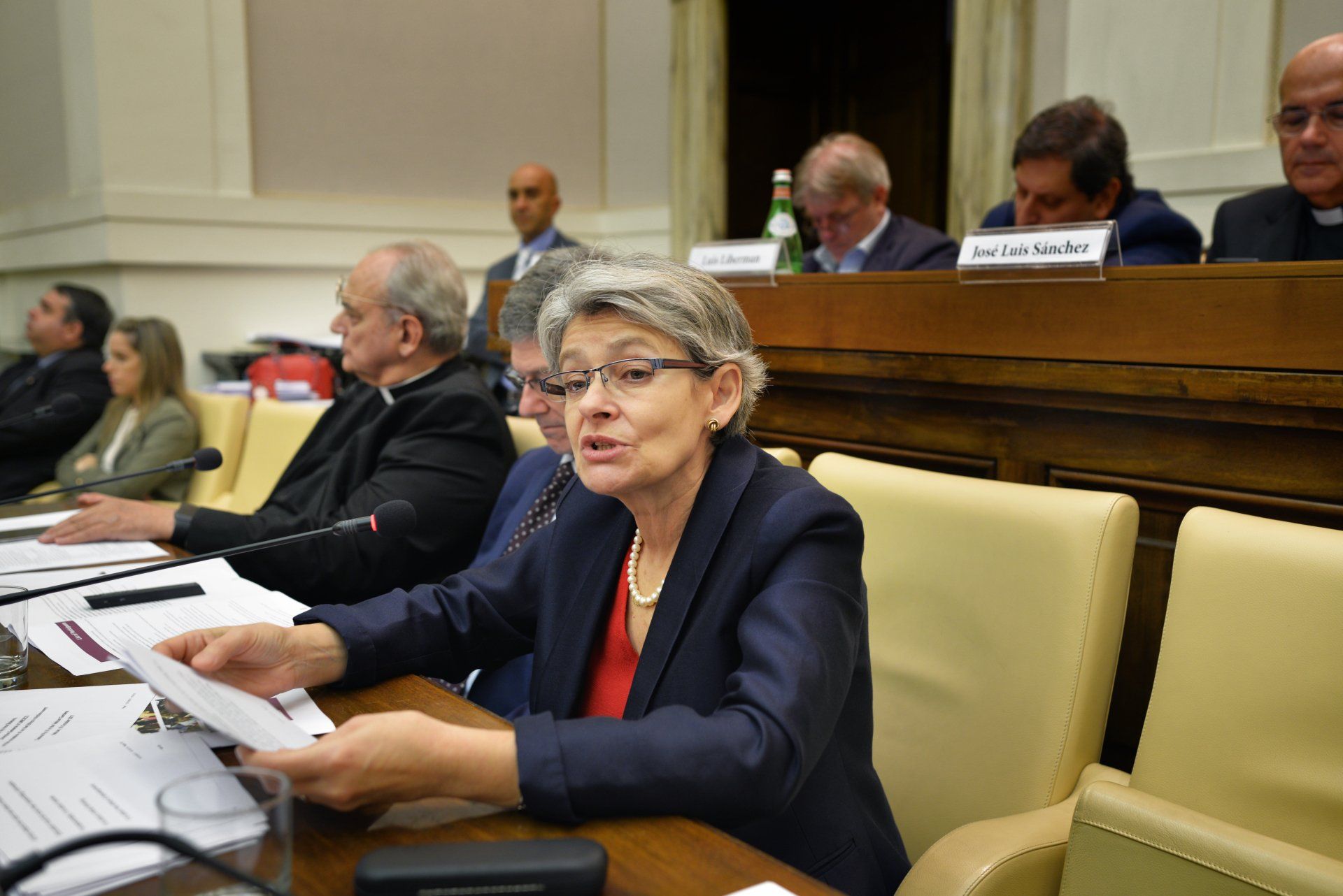 A woman is sitting at a table talking to a group of people.