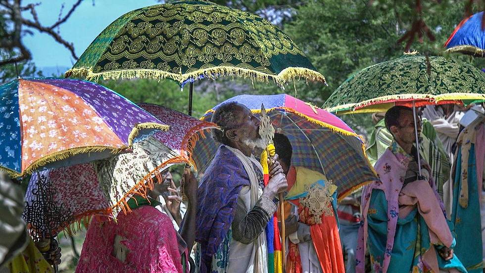 A group of people are standing under colorful umbrellas.